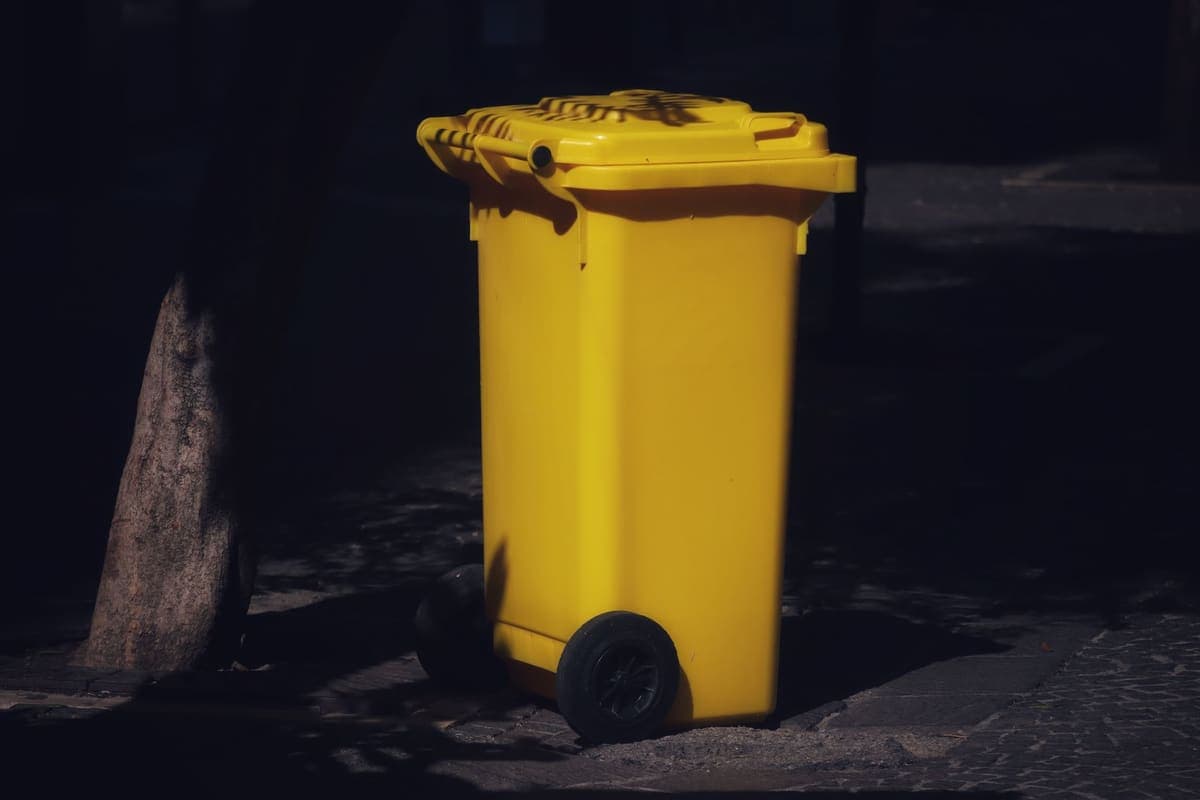Two-wheel curbside trash cart on a street in low sunlight