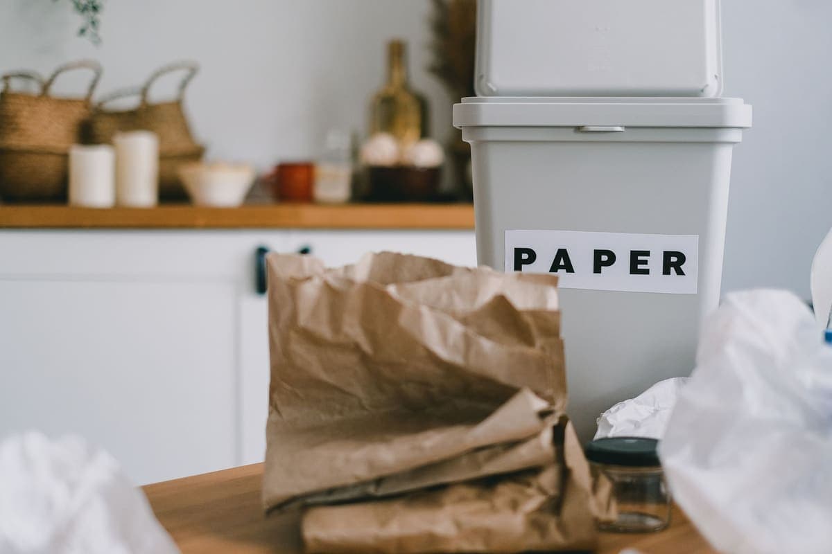 Small white kitchen bin beside paper bags on a wooden counter