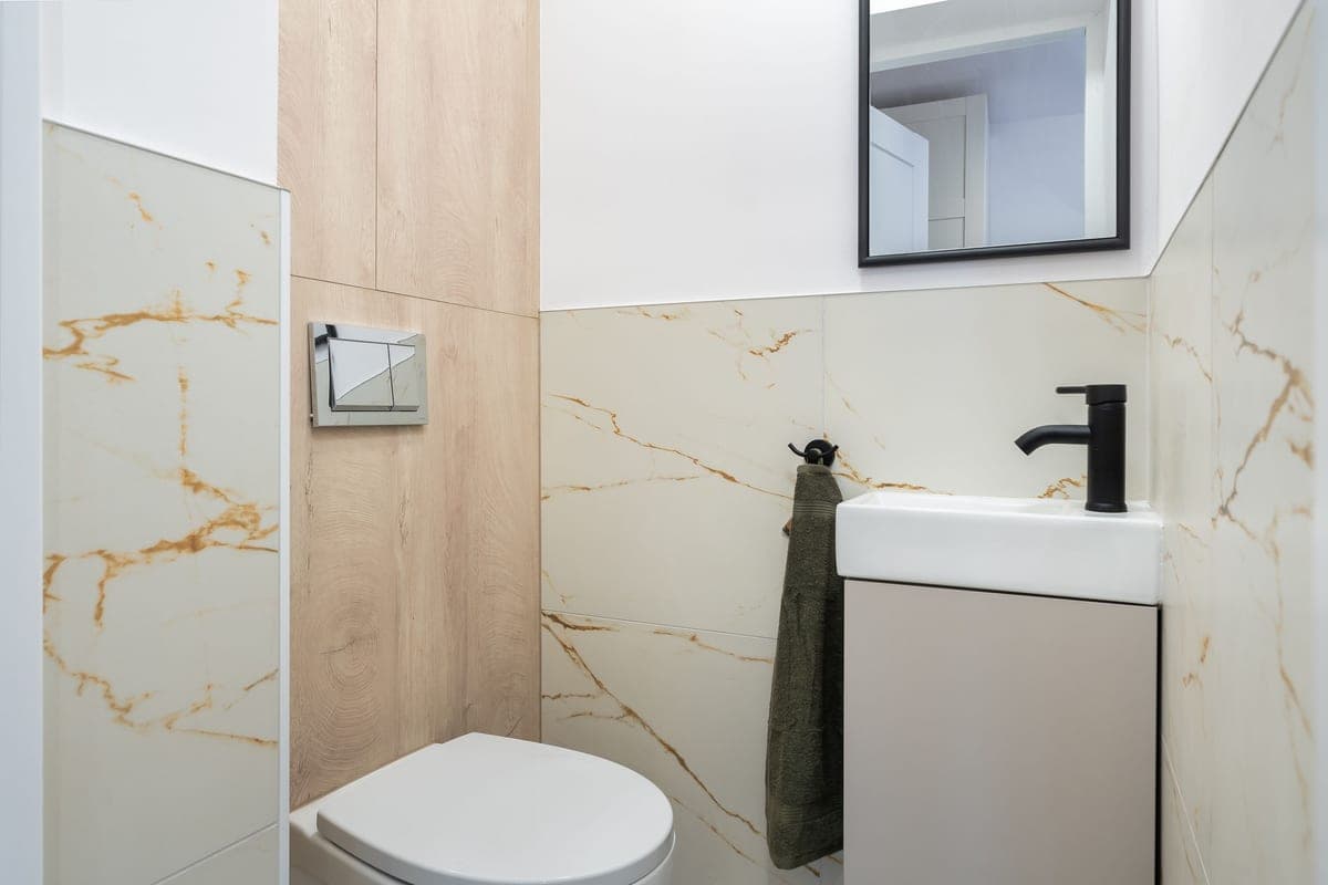 Small white waste bin beside a bathroom basin