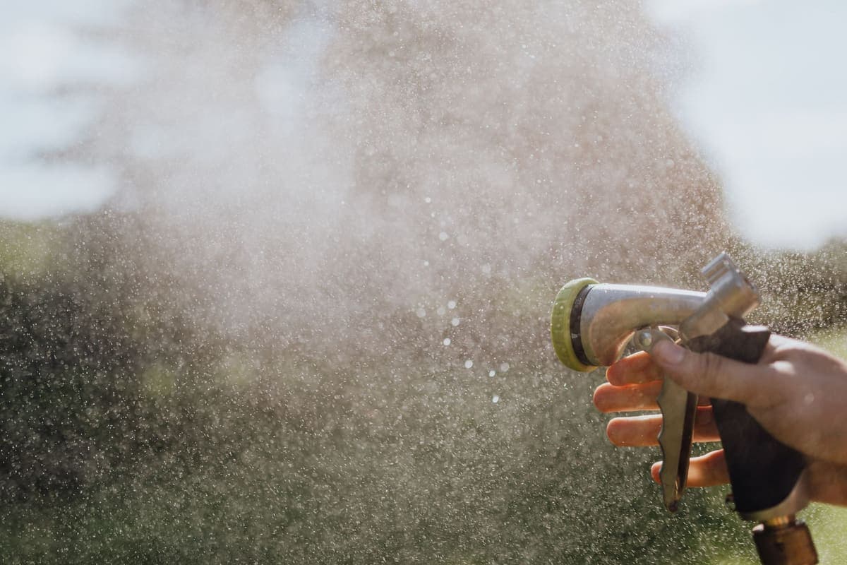 A hand holding a garden hose spray nozzle