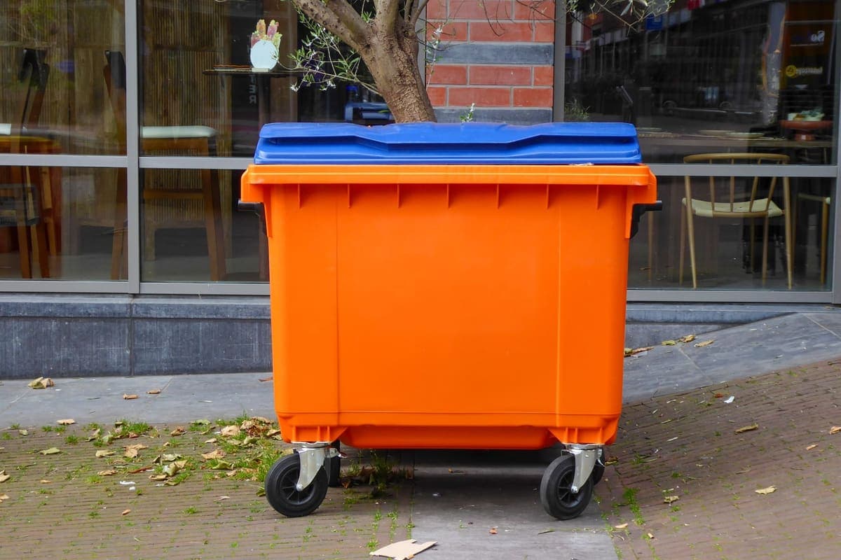 Large commercial wheeled waste container outside a building
