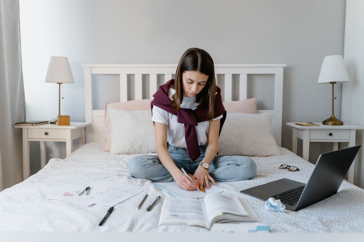 Student working on a bed in a small study bedroom