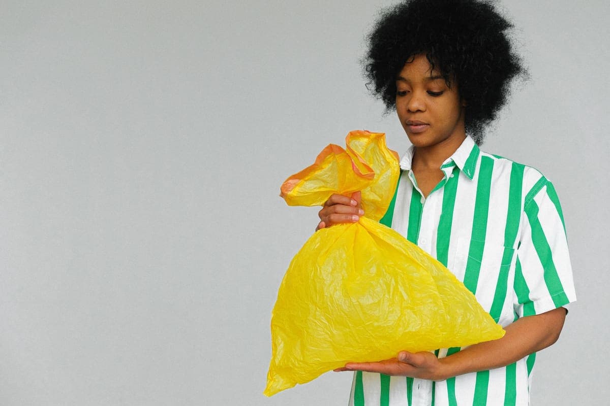A person carrying a tied plastic rubbish bag
