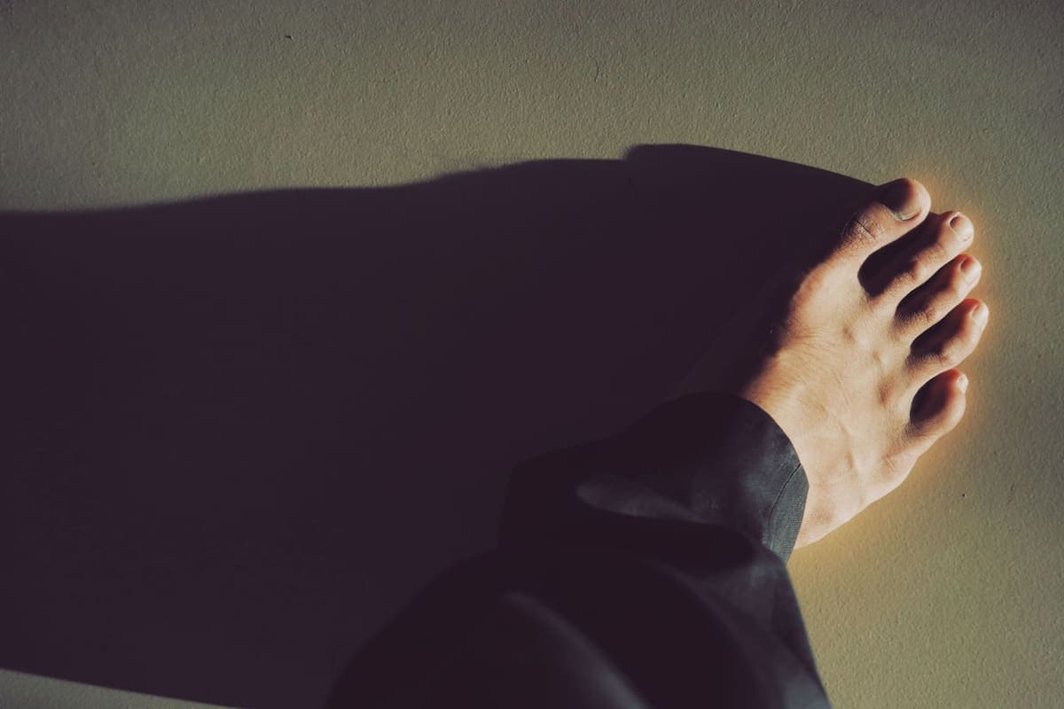 A bare foot on a hard floor beside a cabinet