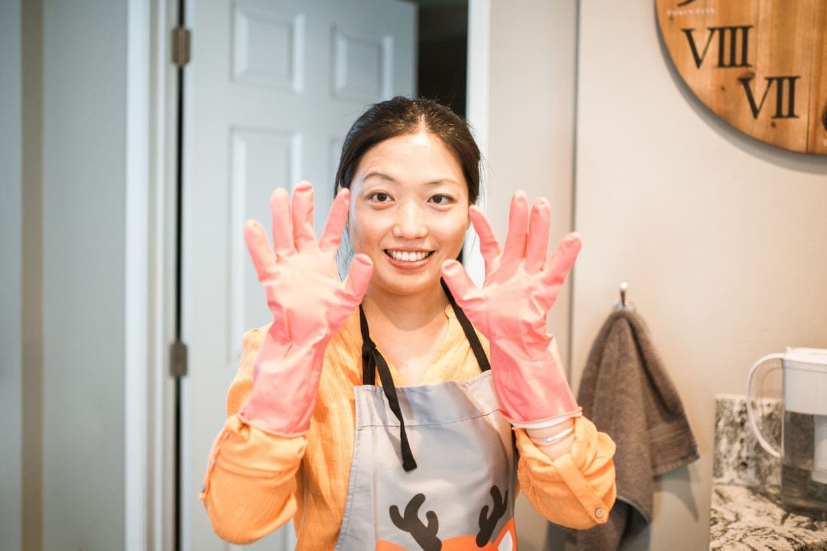 Person cleaning a kitchen surface wearing rubber gloves