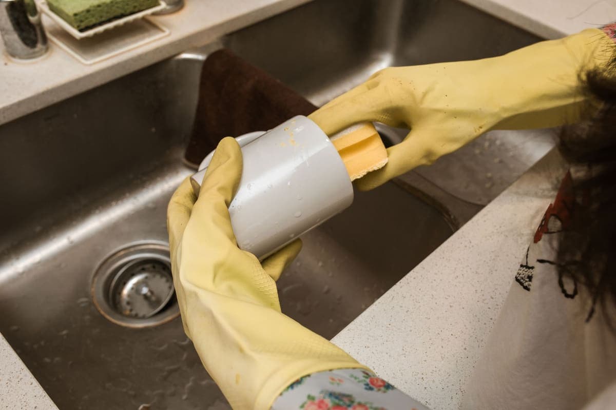 A person washing a mug at a kitchen sink