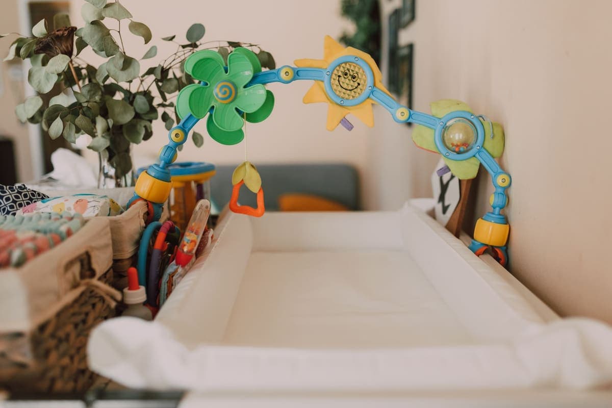 A baby changing mat with a toy arch above it