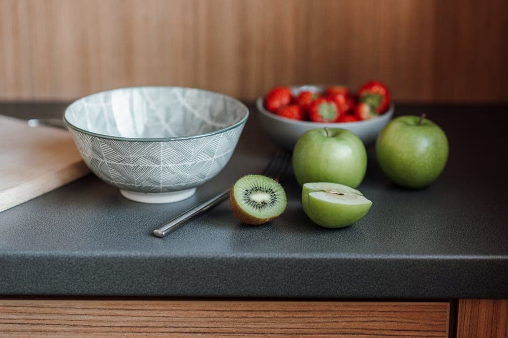 Fruit fly trap on a kitchen counter beside a fruit bowl